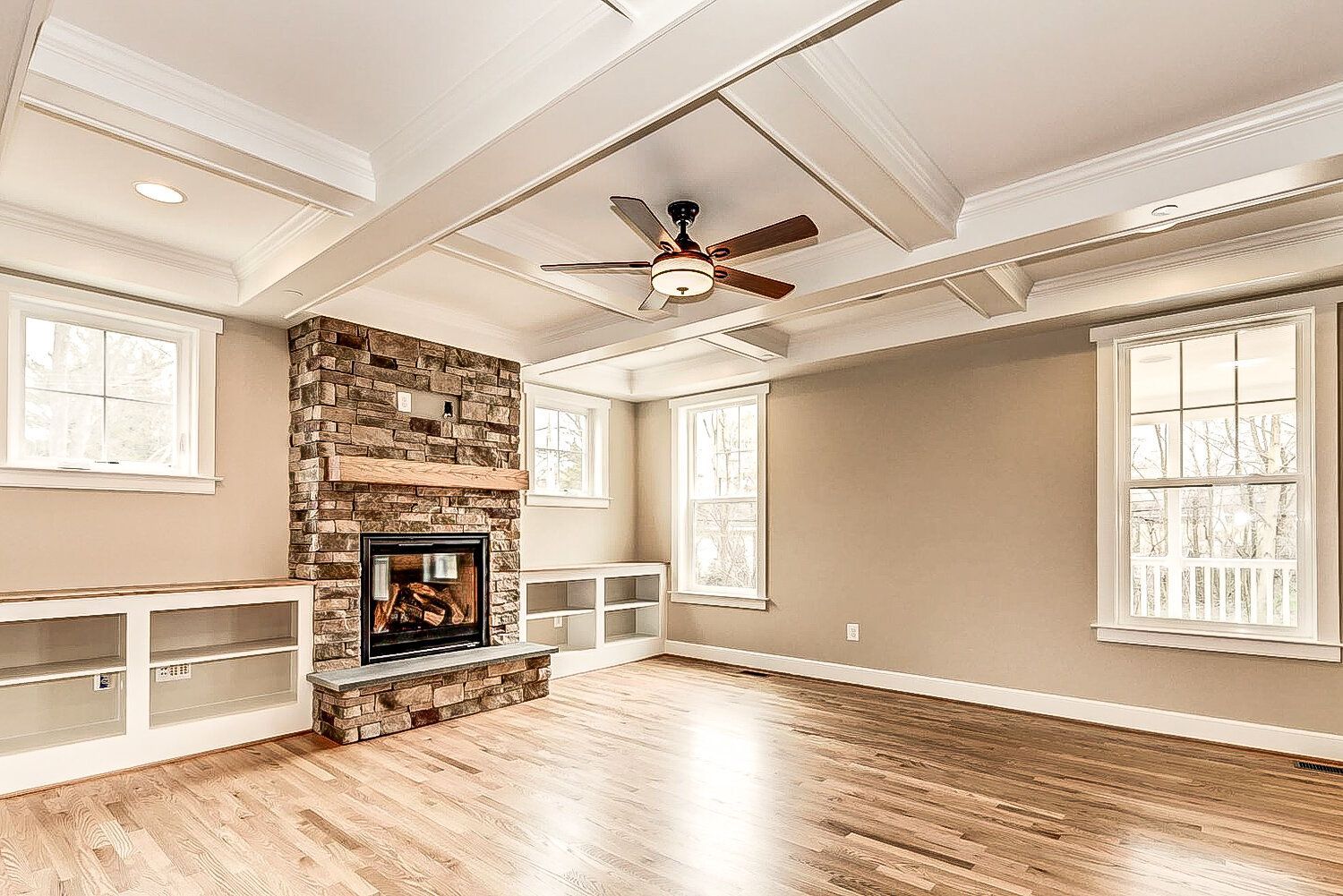 An empty living room with a fireplace and a ceiling fan.