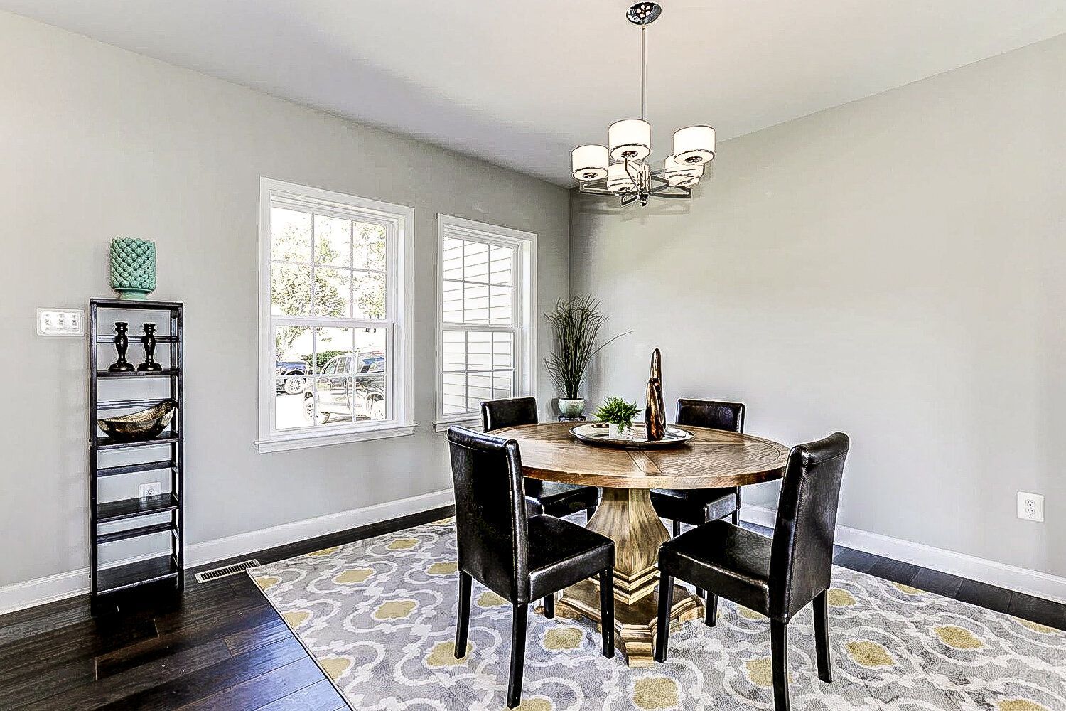 A dining room with a round table and chairs and a chandelier.