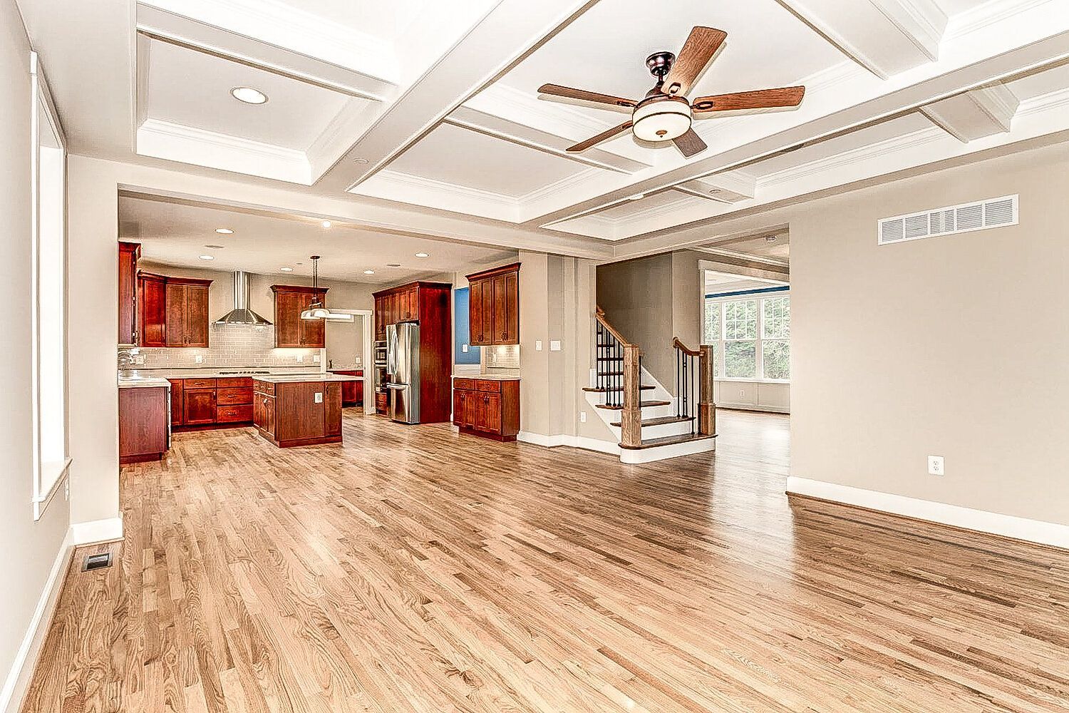 A large empty room with hardwood floors and a ceiling fan.