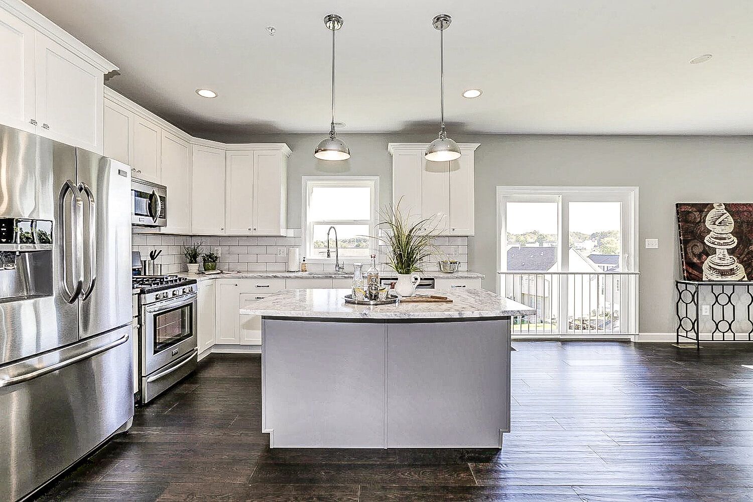 A kitchen with stainless steel appliances , white cabinets , and a large island.
