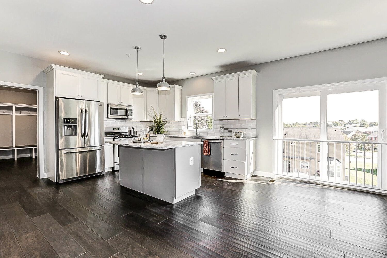 A kitchen with white cabinets , stainless steel appliances , a large island , and hardwood floors.