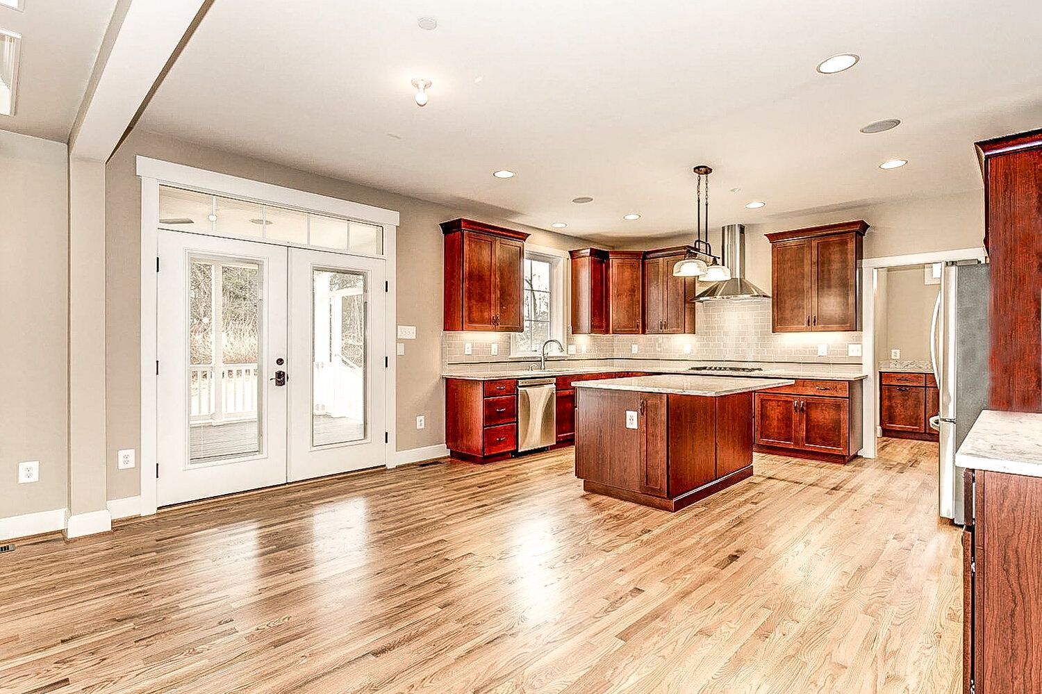 A large empty kitchen with hardwood floors and stainless steel appliances.