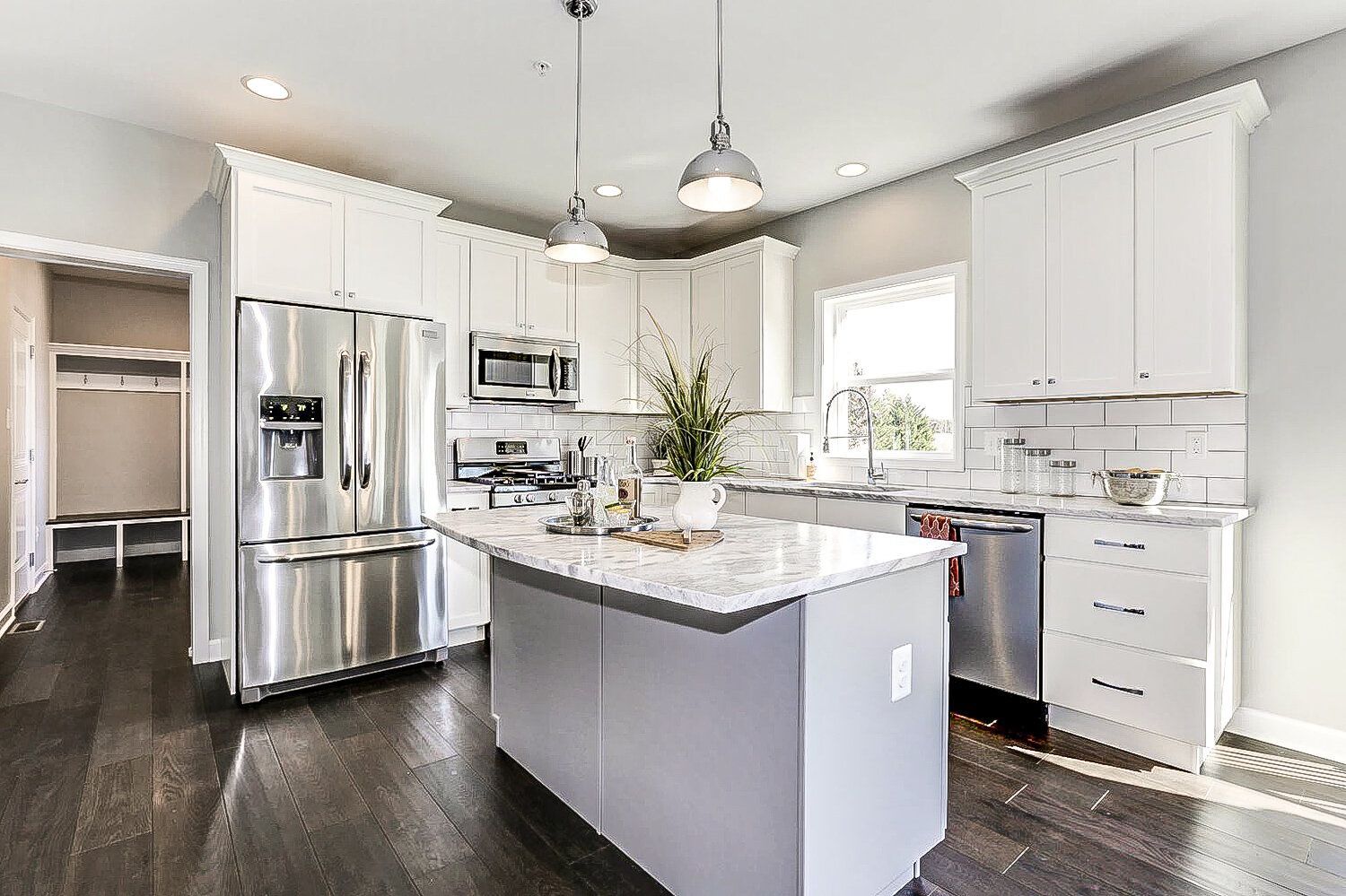 A kitchen with white cabinets , stainless steel appliances , and a large island.