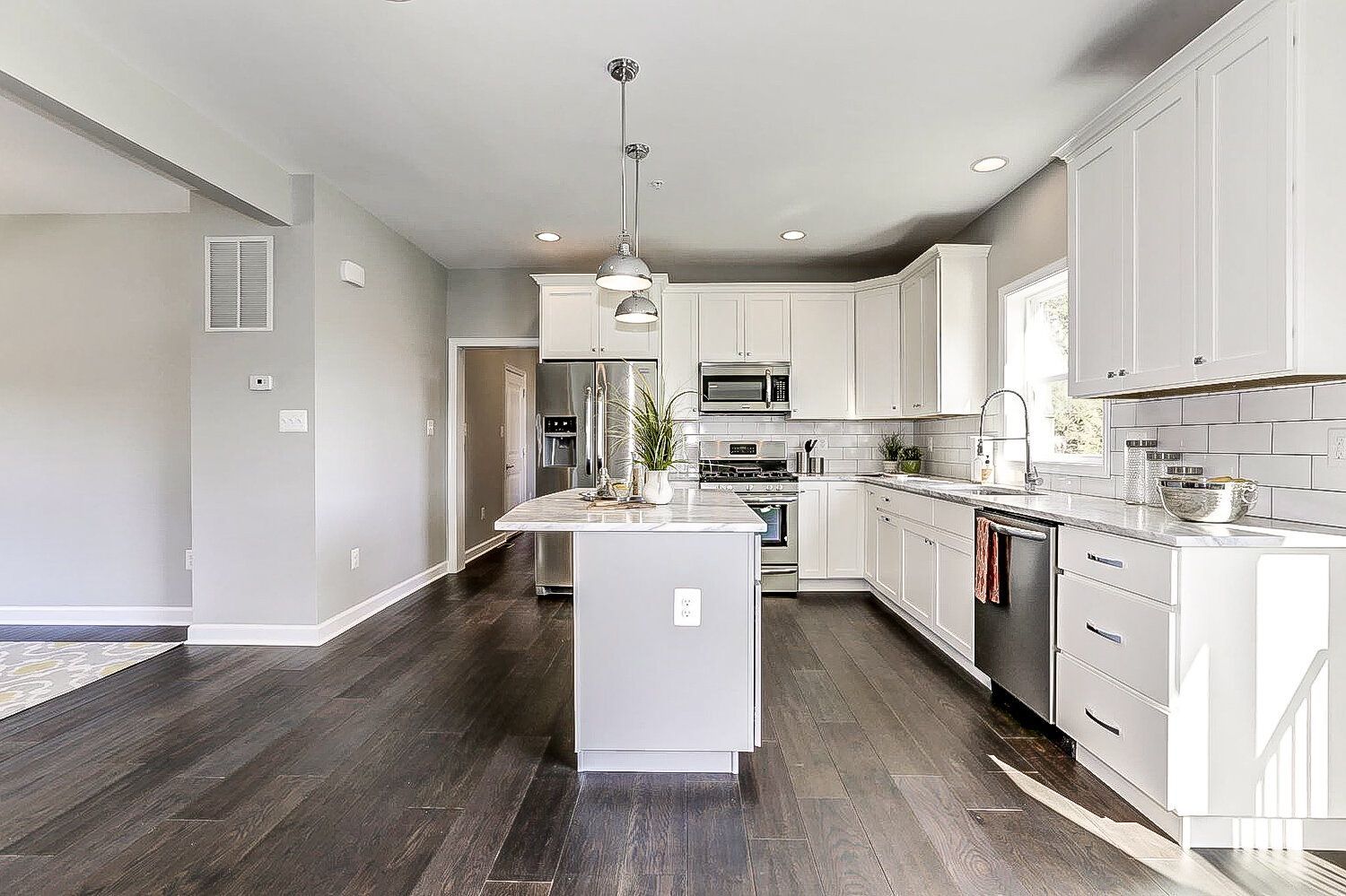A kitchen with white cabinets , stainless steel appliances , and a large island.