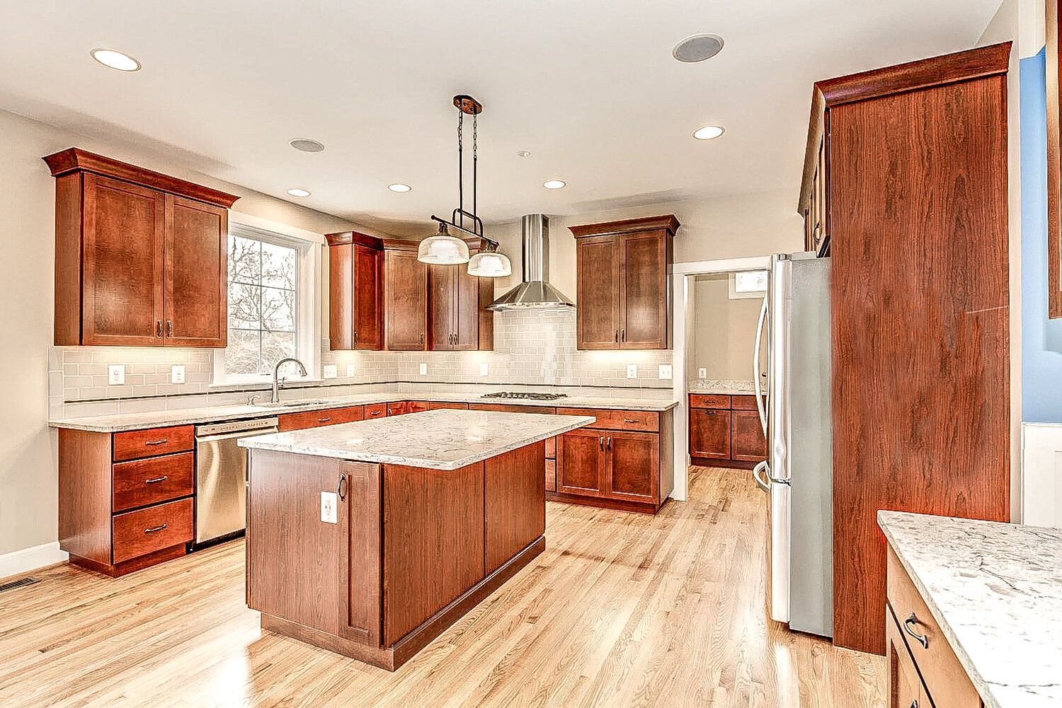 A kitchen with wooden cabinets , granite counter tops , stainless steel appliances and a large island.