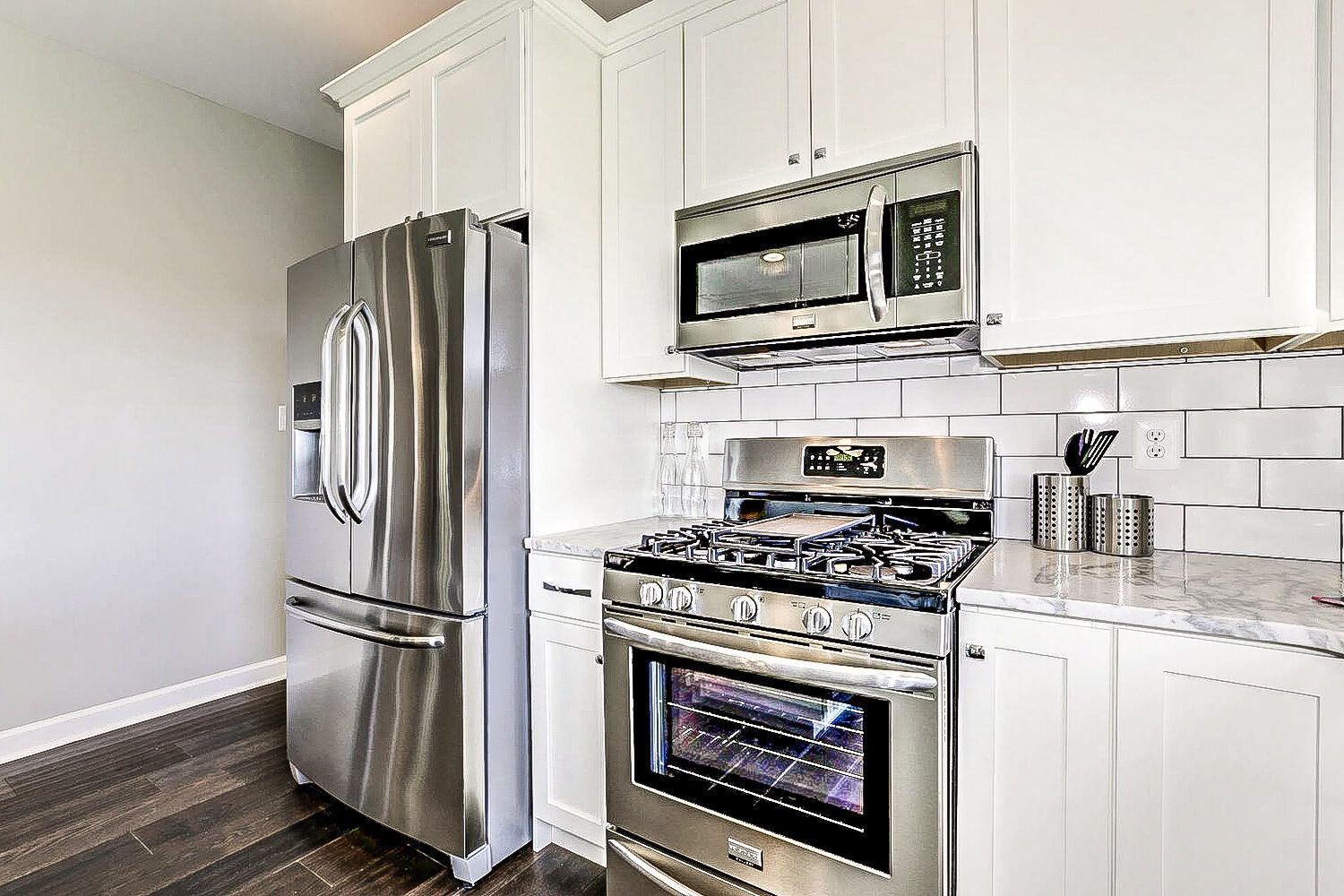A kitchen with stainless steel appliances and white cabinets.