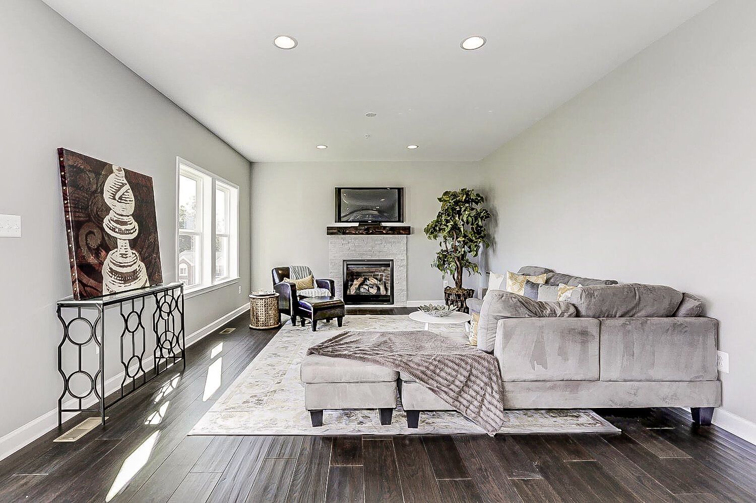 A living room with a couch , chairs , ottoman and fireplace.