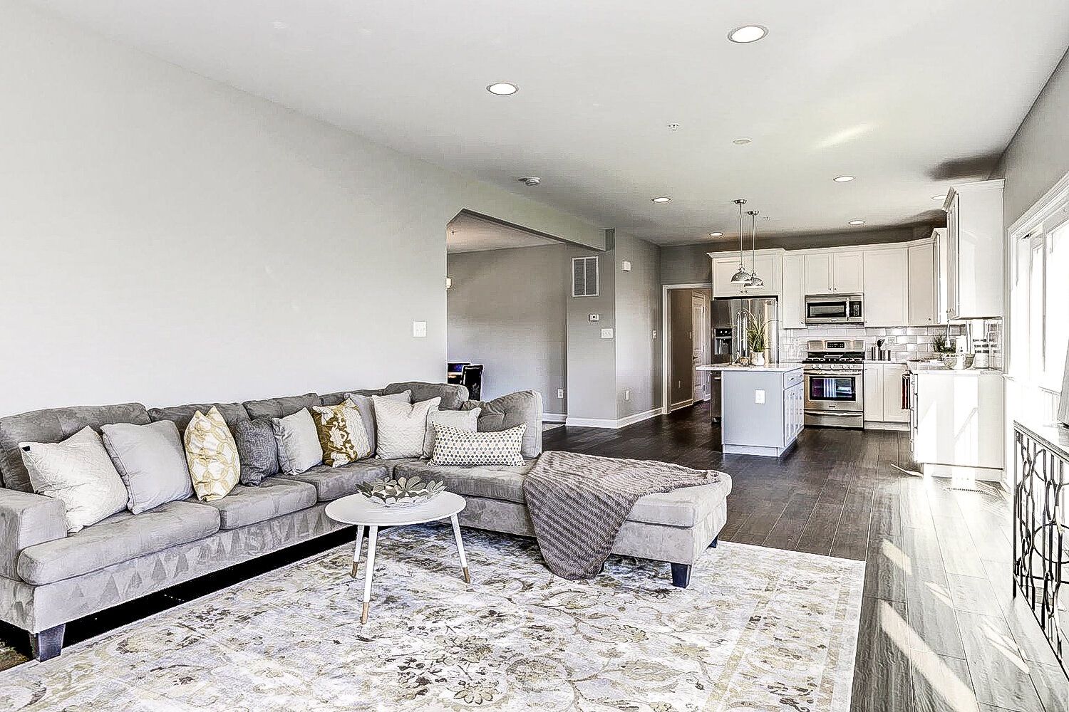 A living room with a large sectional couch and a rug.