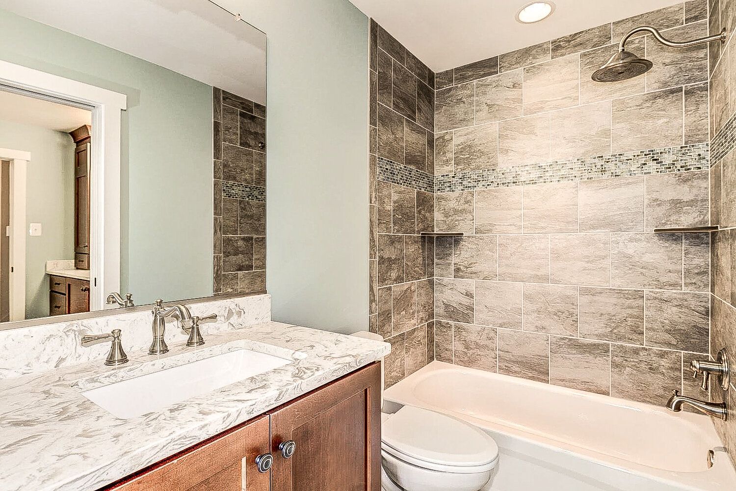 A bathroom with a sink , toilet , tub and mirror.