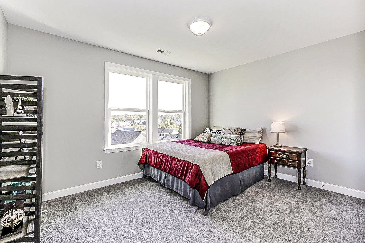 A bedroom with a bed , nightstand , and two windows.