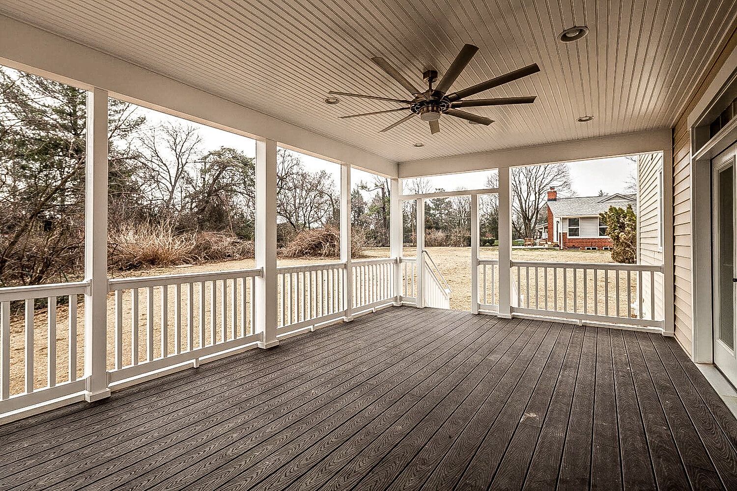 There is a ceiling fan on the porch of a house.