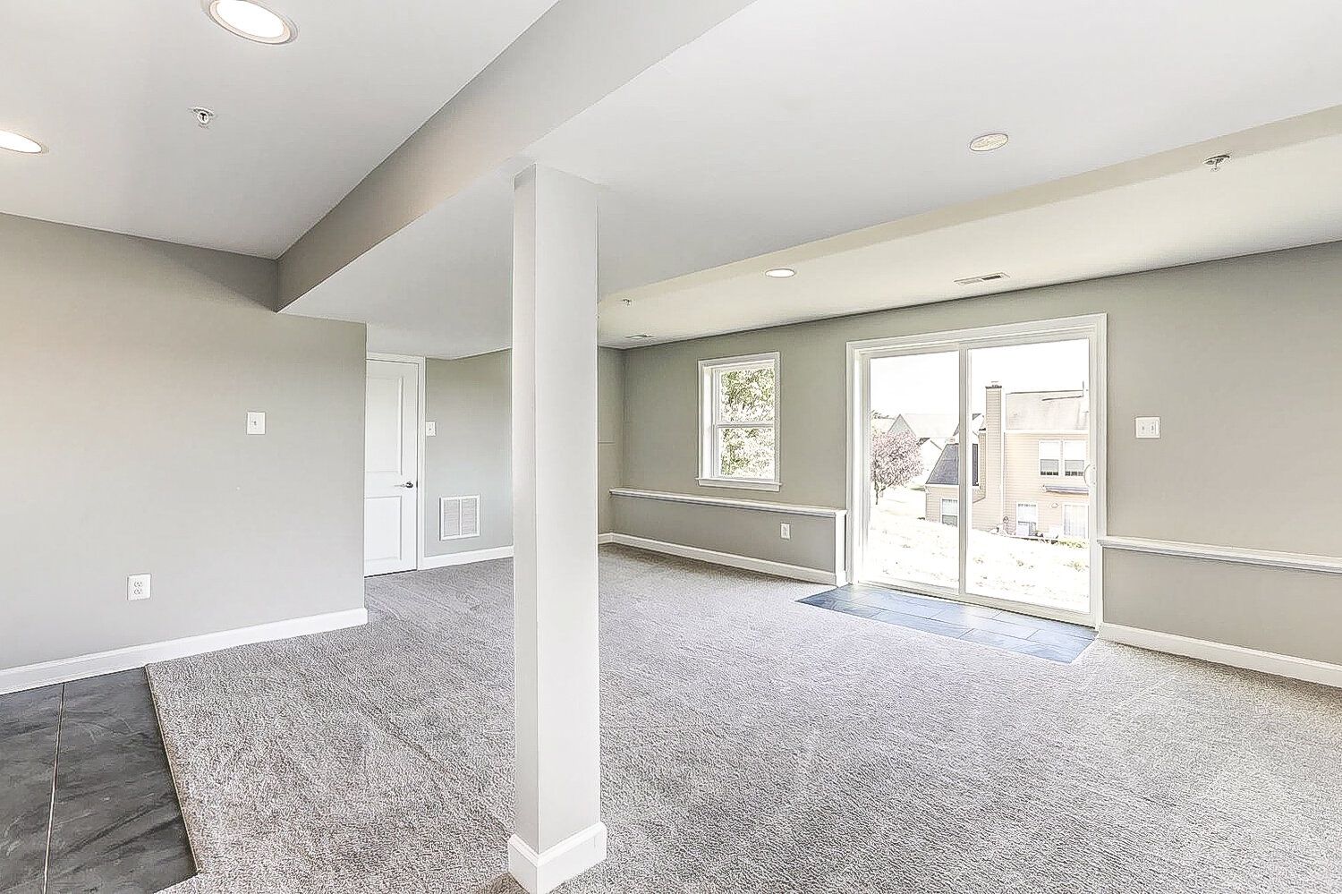 An empty basement with a sliding glass door and a pillar.