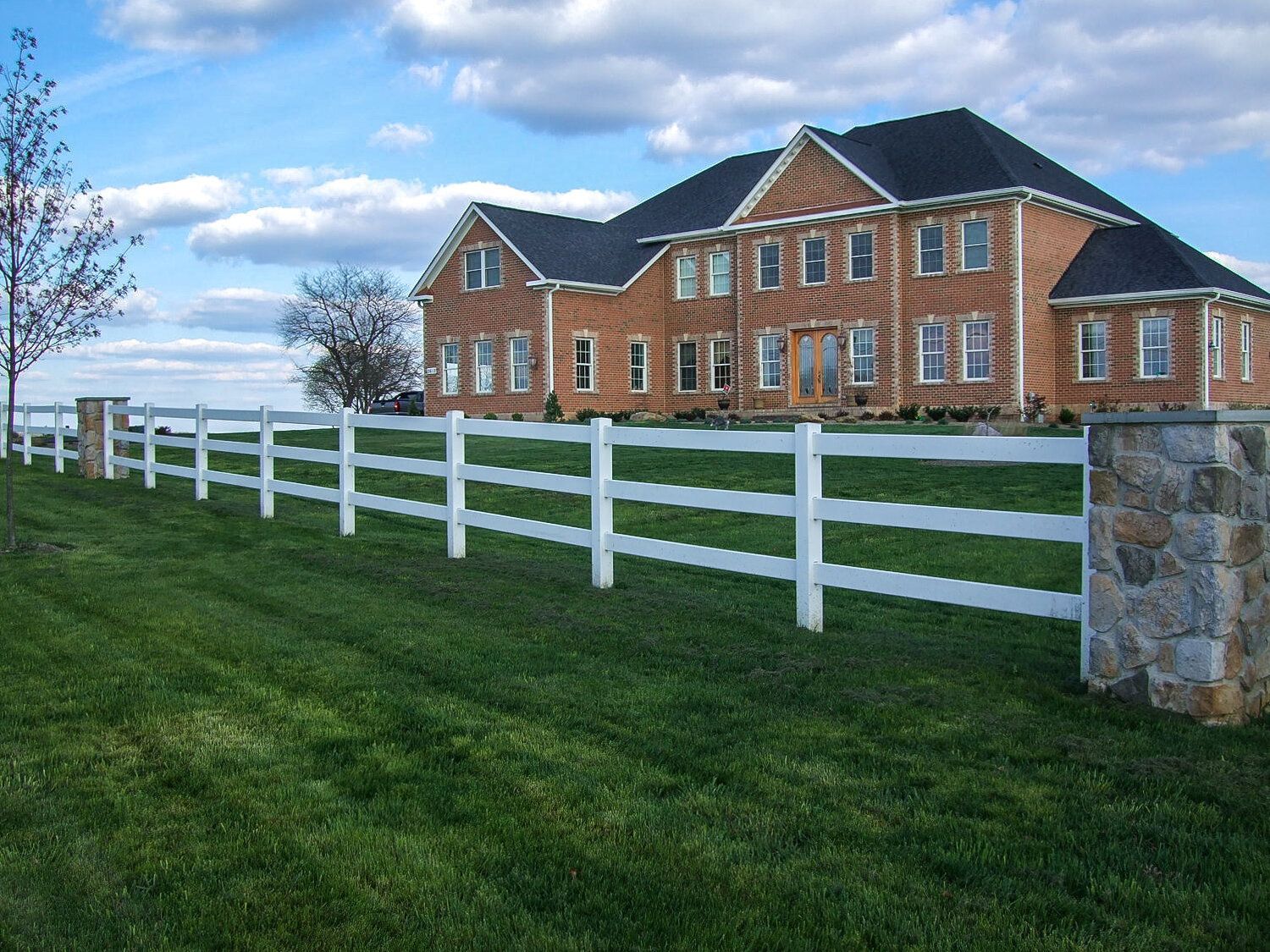 A large brick house with a white fence in front of it