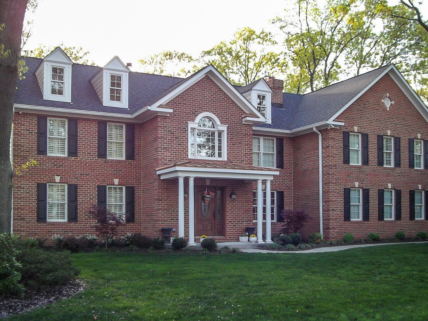 A large brick house with black shutters on the windows