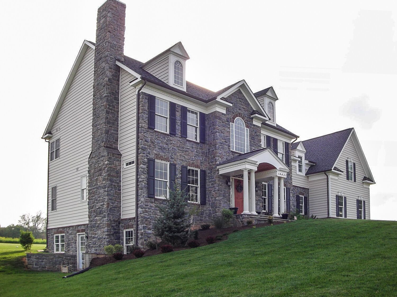 A large house is sitting on top of a lush green hill.
