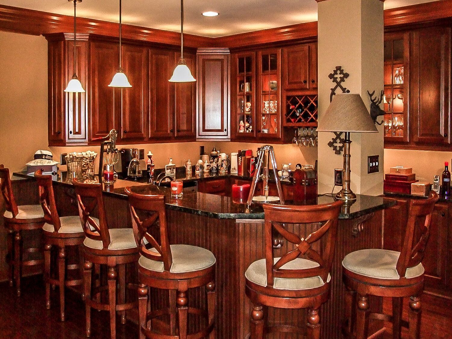 A kitchen with a bar and chairs and a lamp