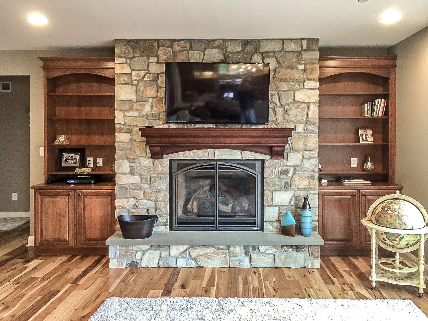 A living room with a stone fireplace and a flat screen tv.