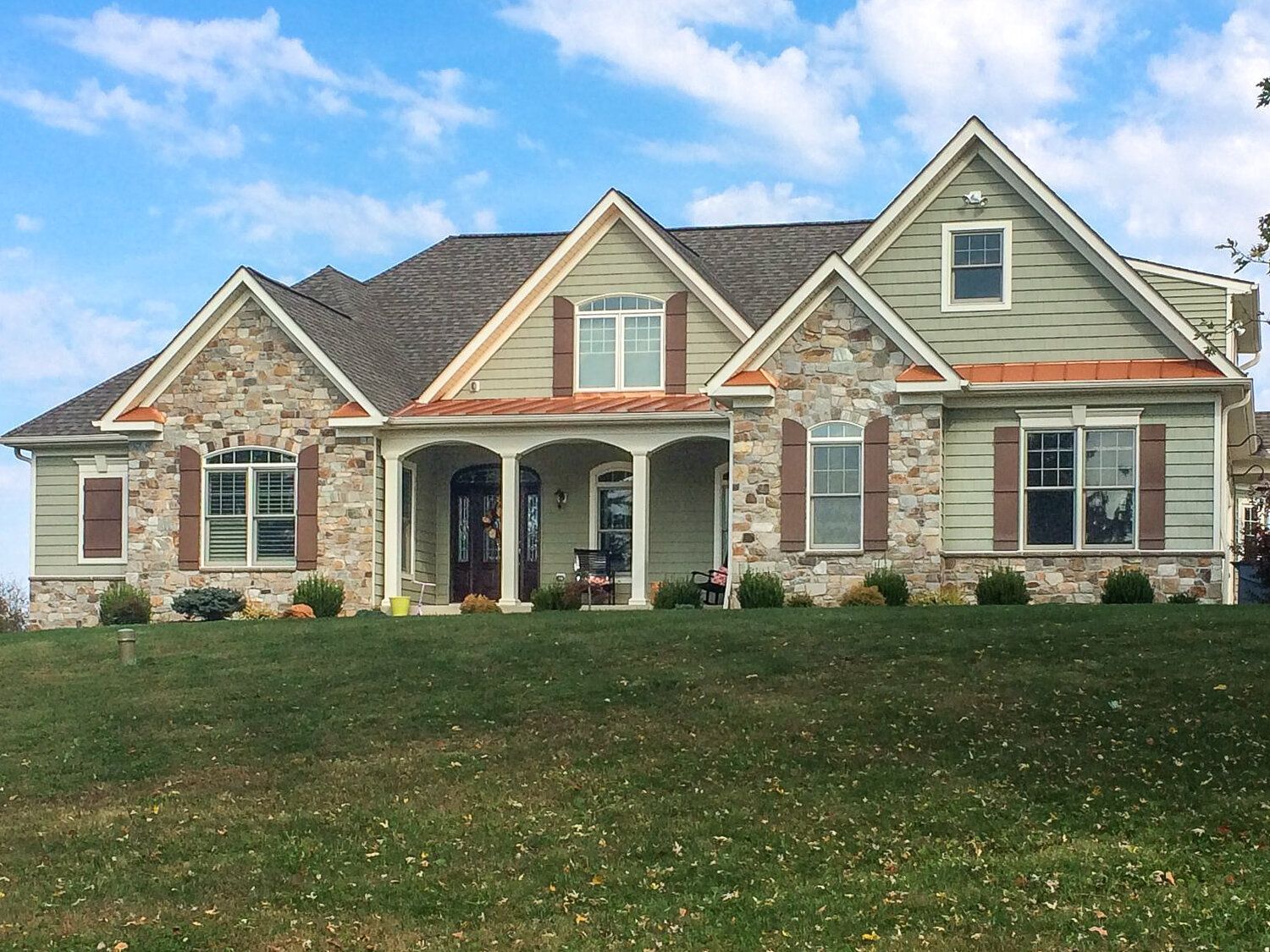 A large house sits on top of a lush green hillside