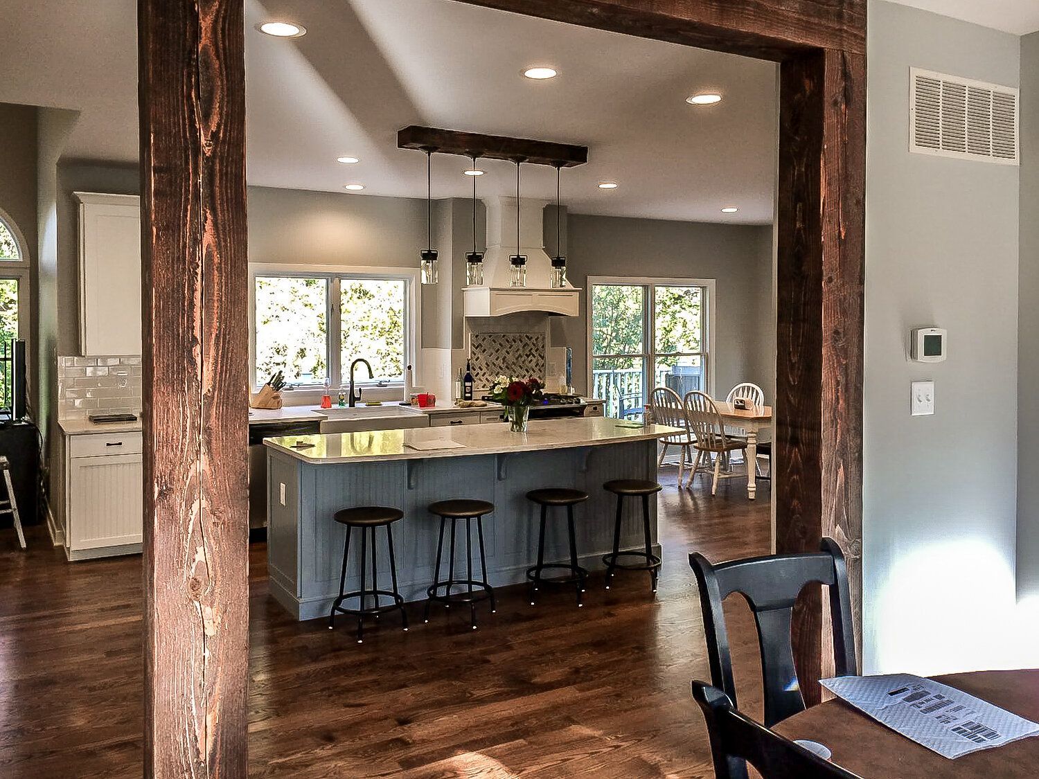 A kitchen and dining room are connected by a wooden beam.