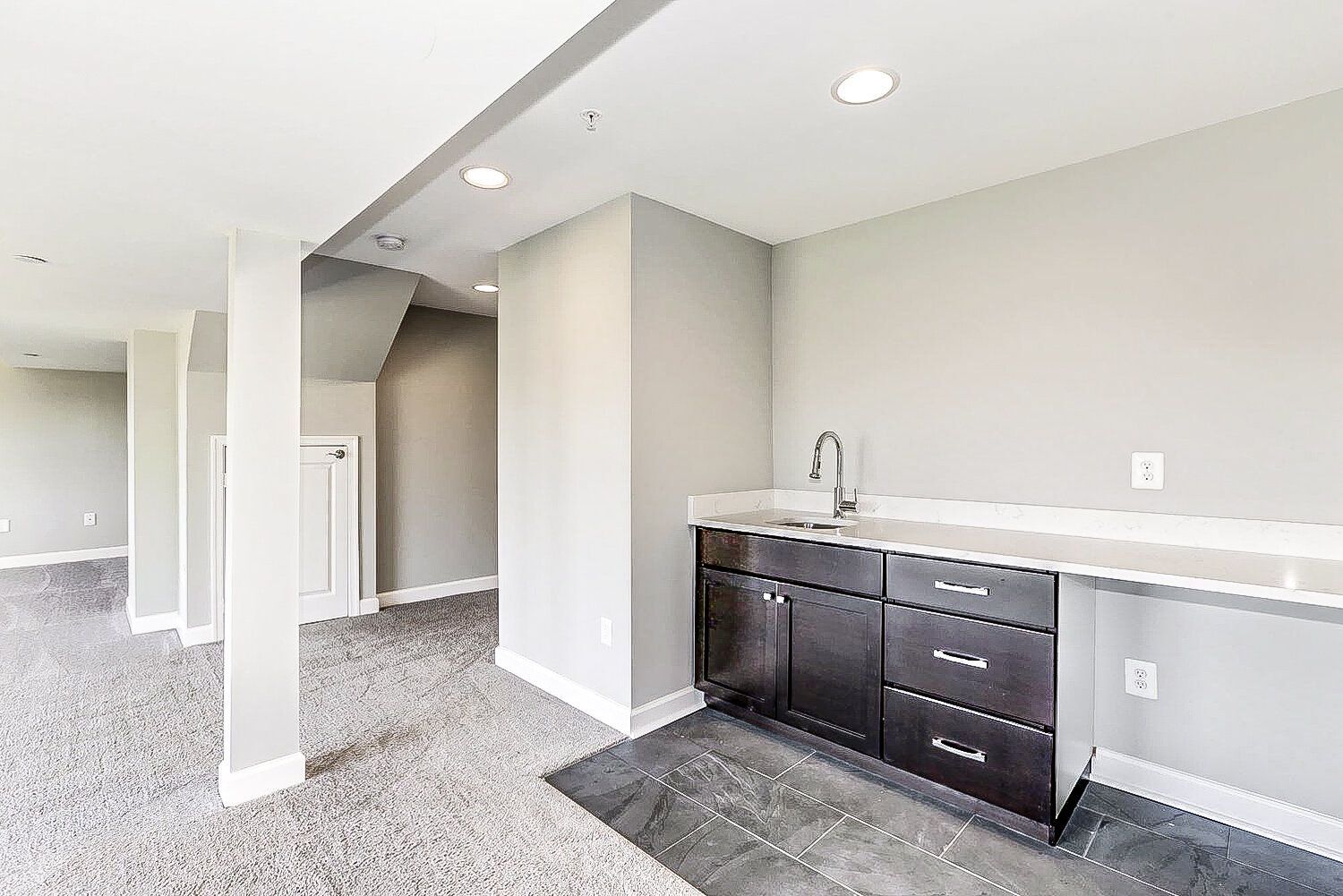 A basement with a sink and cabinets in it.