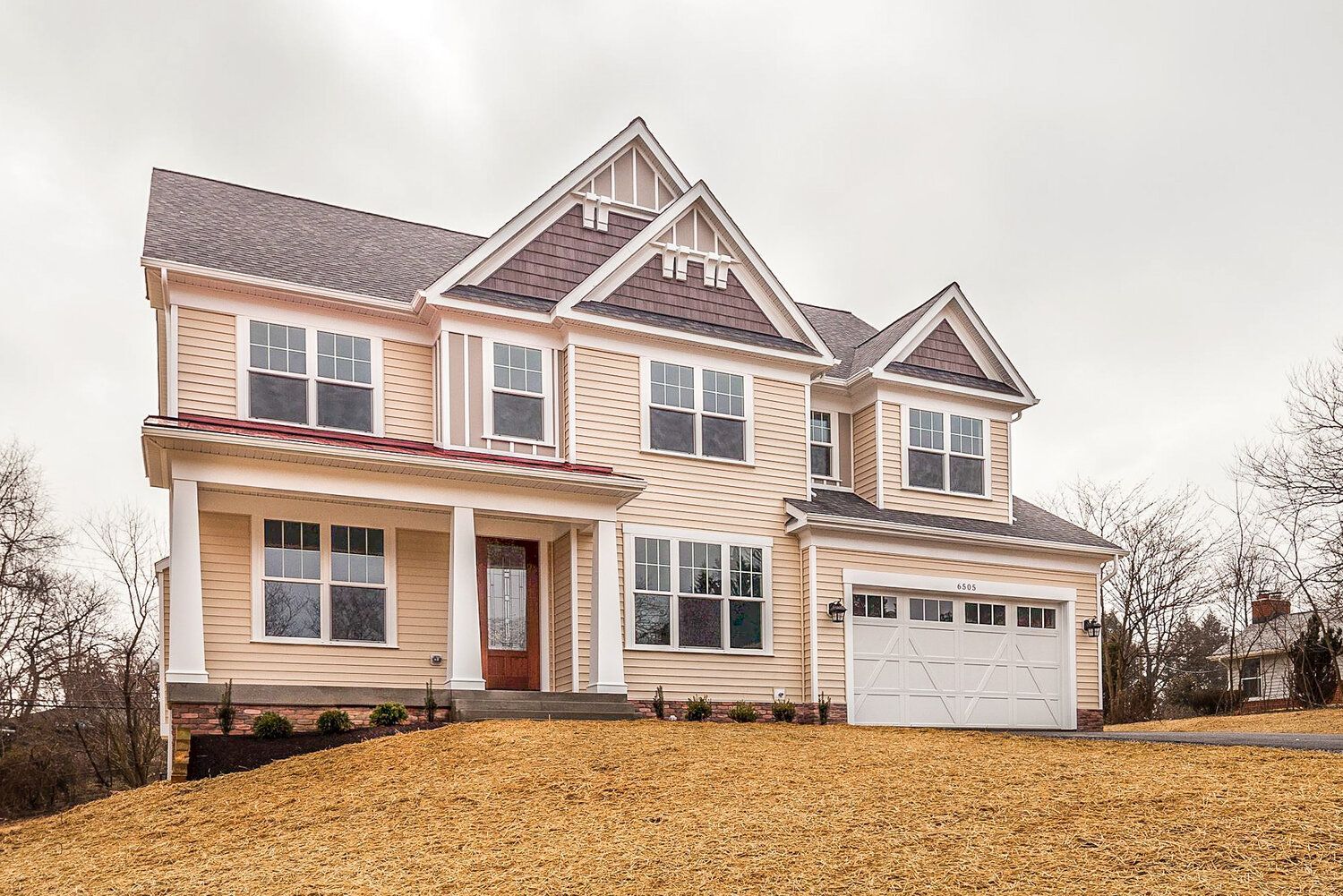 A large house with a garage and a lot of windows is sitting on top of a hill.