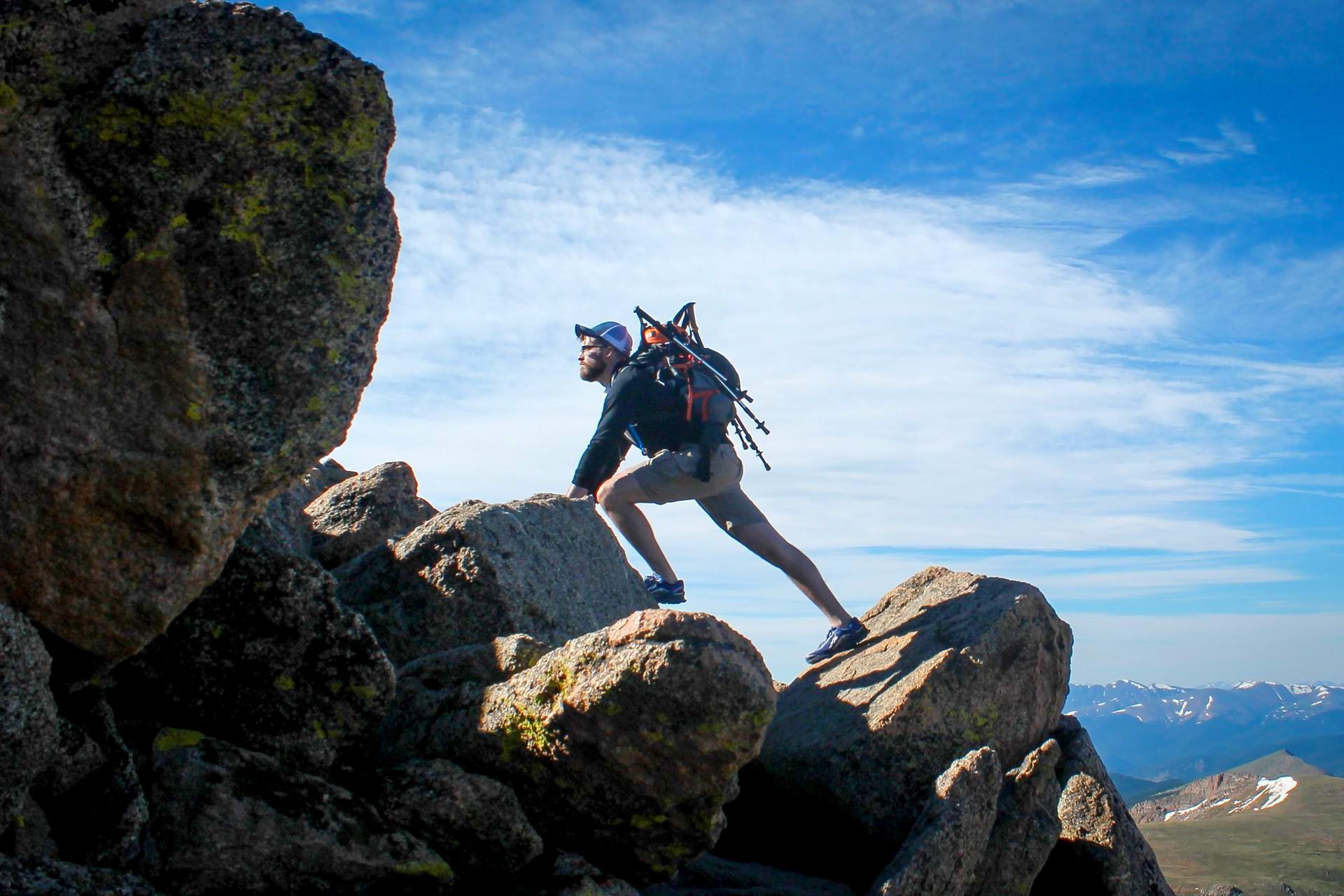 A man with a backpack is climbing up a rocky cliff.