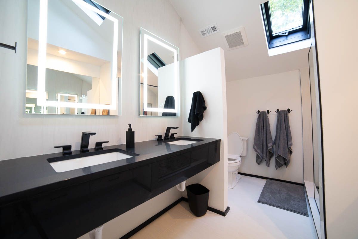 A bathroom with a toilet , sink , mirror and shower.