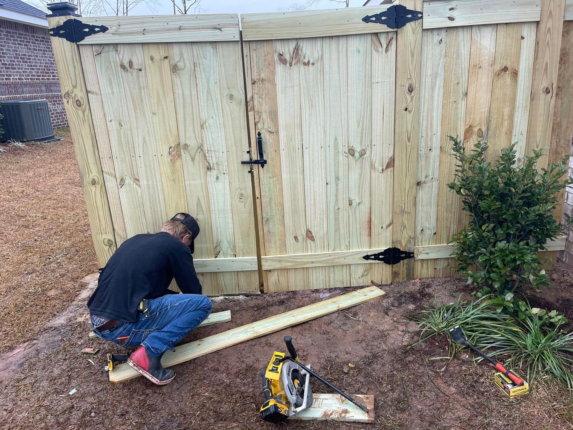 A Man Is Working on A Wooden Fence with A Circular Saw - Mississippi, United States - Magnolia Fencing, LLC