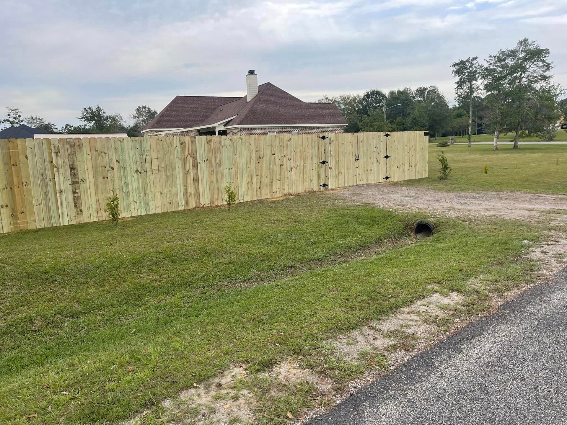 A Wooden Fence with A House in The Background - Mississippi, United States - Magnolia Fencing, LLC