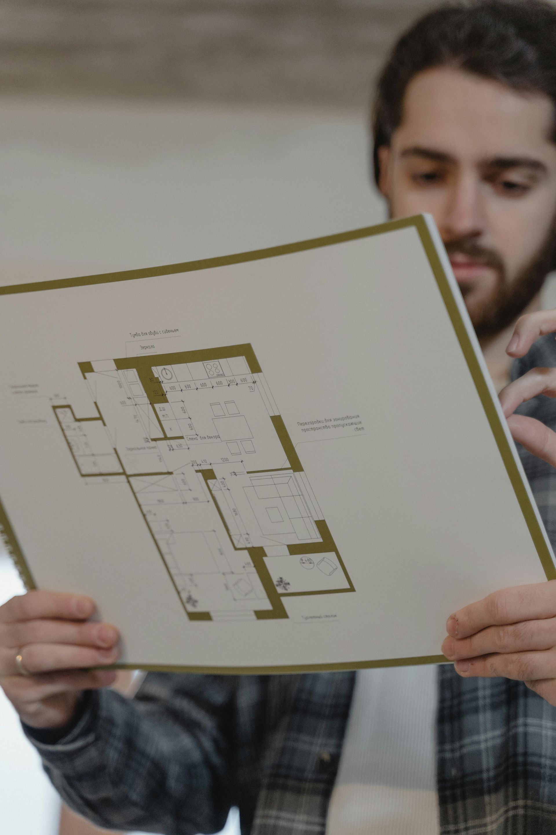 Man examining architectural blueprints indoors.