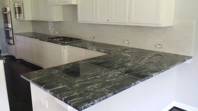 U-shaped kitchen with white cabinets, dark granite countertops, and dark hardwood floors.