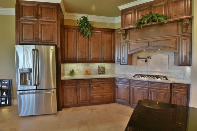 Kitchen with brown cabinets, stainless steel refrigerator, and stovetop.