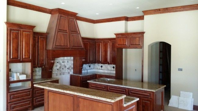 Kitchen with dark wood cabinets, a range hood, and granite countertops.