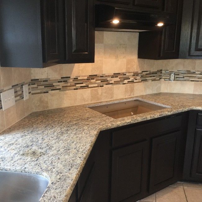 Dark-brown kitchen cabinets with granite countertops and a tile backsplash.
