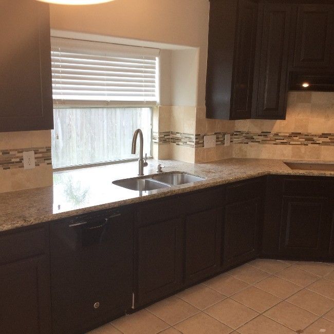 Dark brown kitchen cabinets, granite countertops, and a window above the sink.