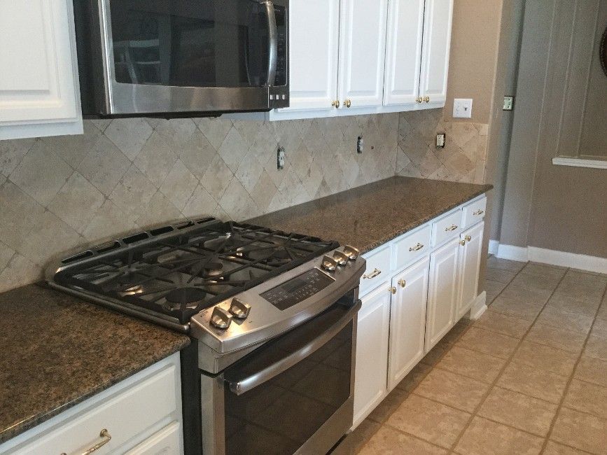 Kitchen with white cabinets, brown countertops, and a stainless steel stove.