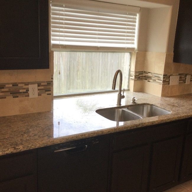 Kitchen with dark cabinets, granite countertop, stainless steel sink, and a window with blinds.