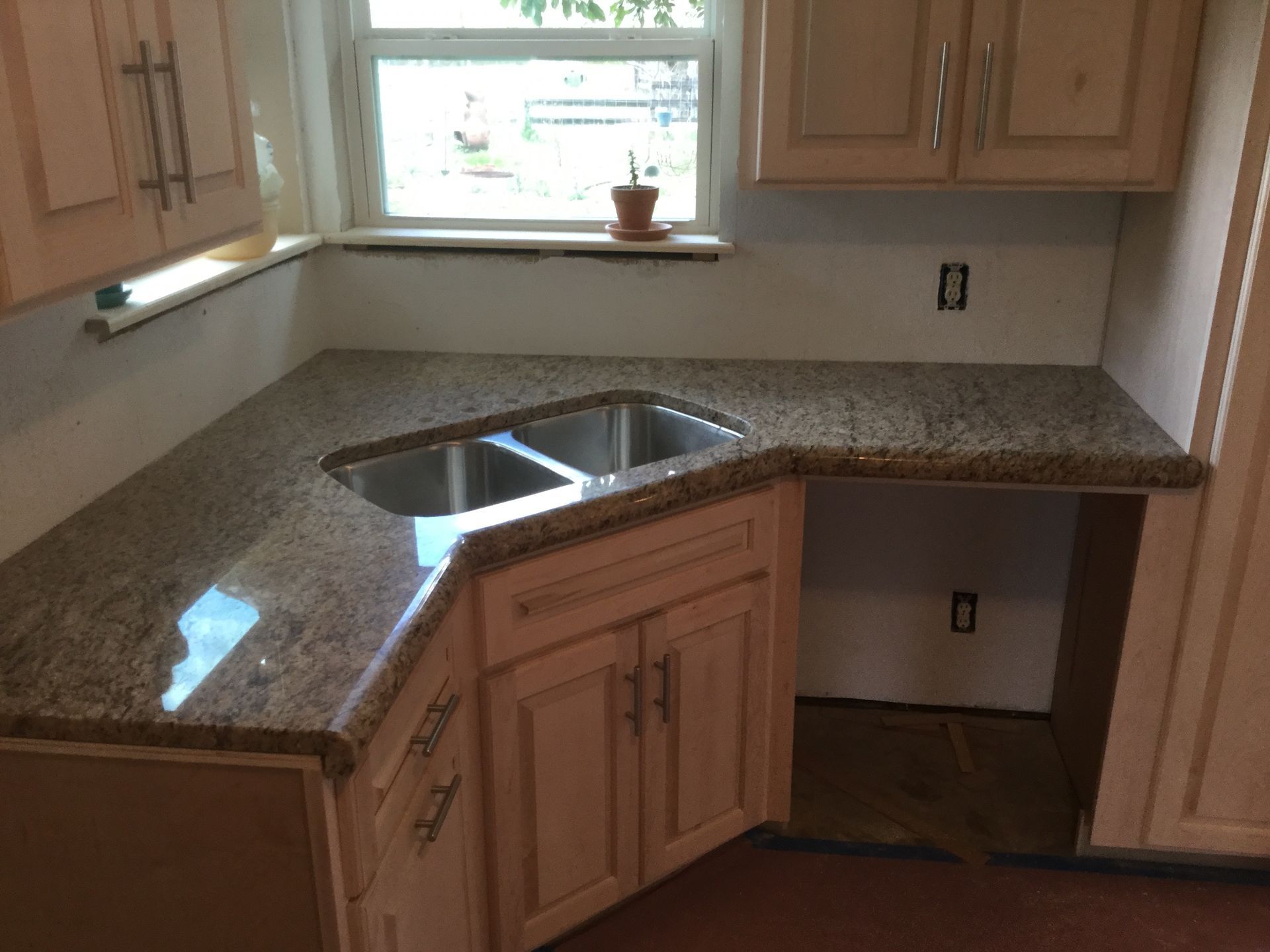 Kitchen corner with granite countertops, cabinets, and a sink.