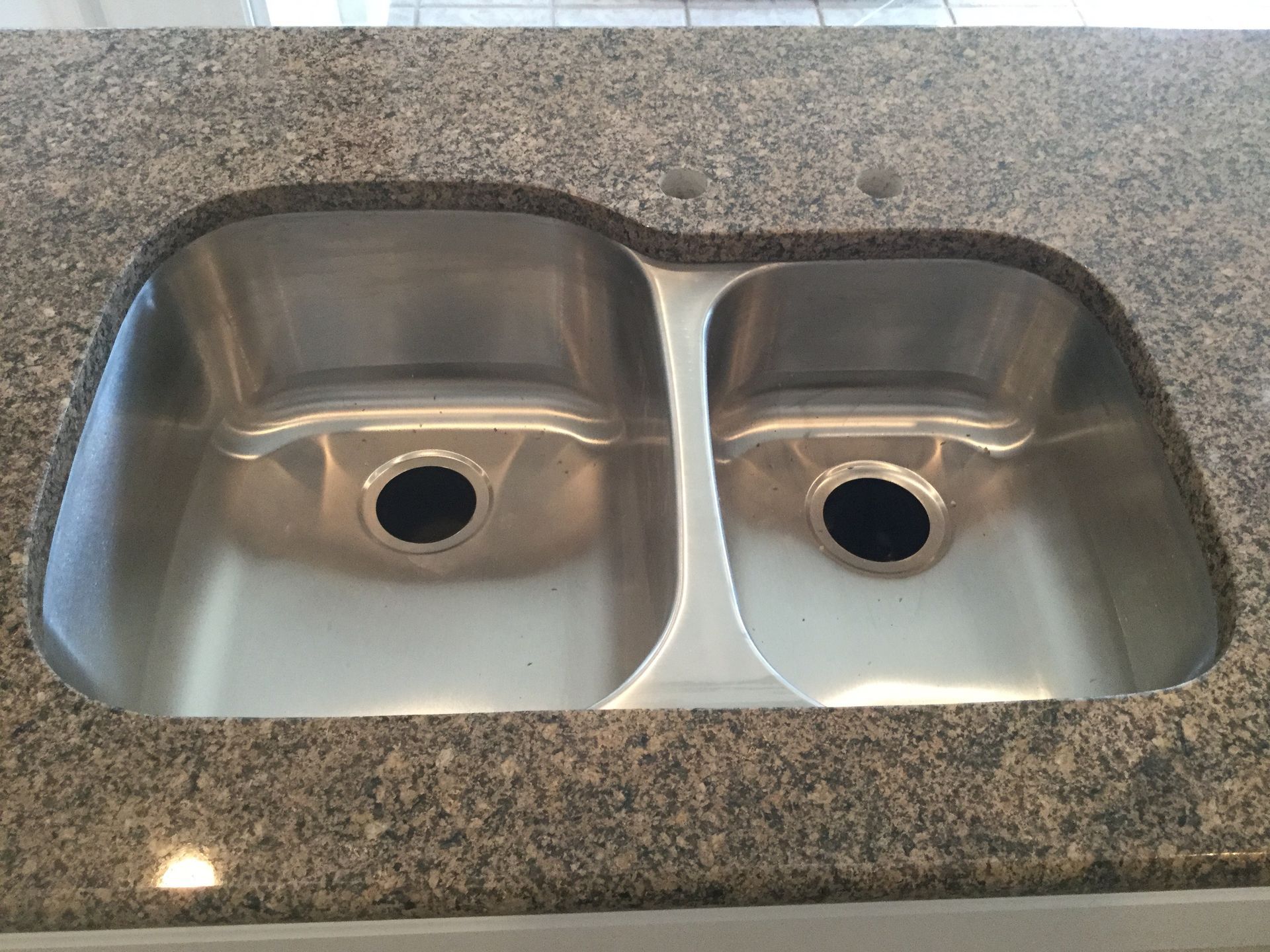 Stainless steel double sink set into a speckled granite countertop.