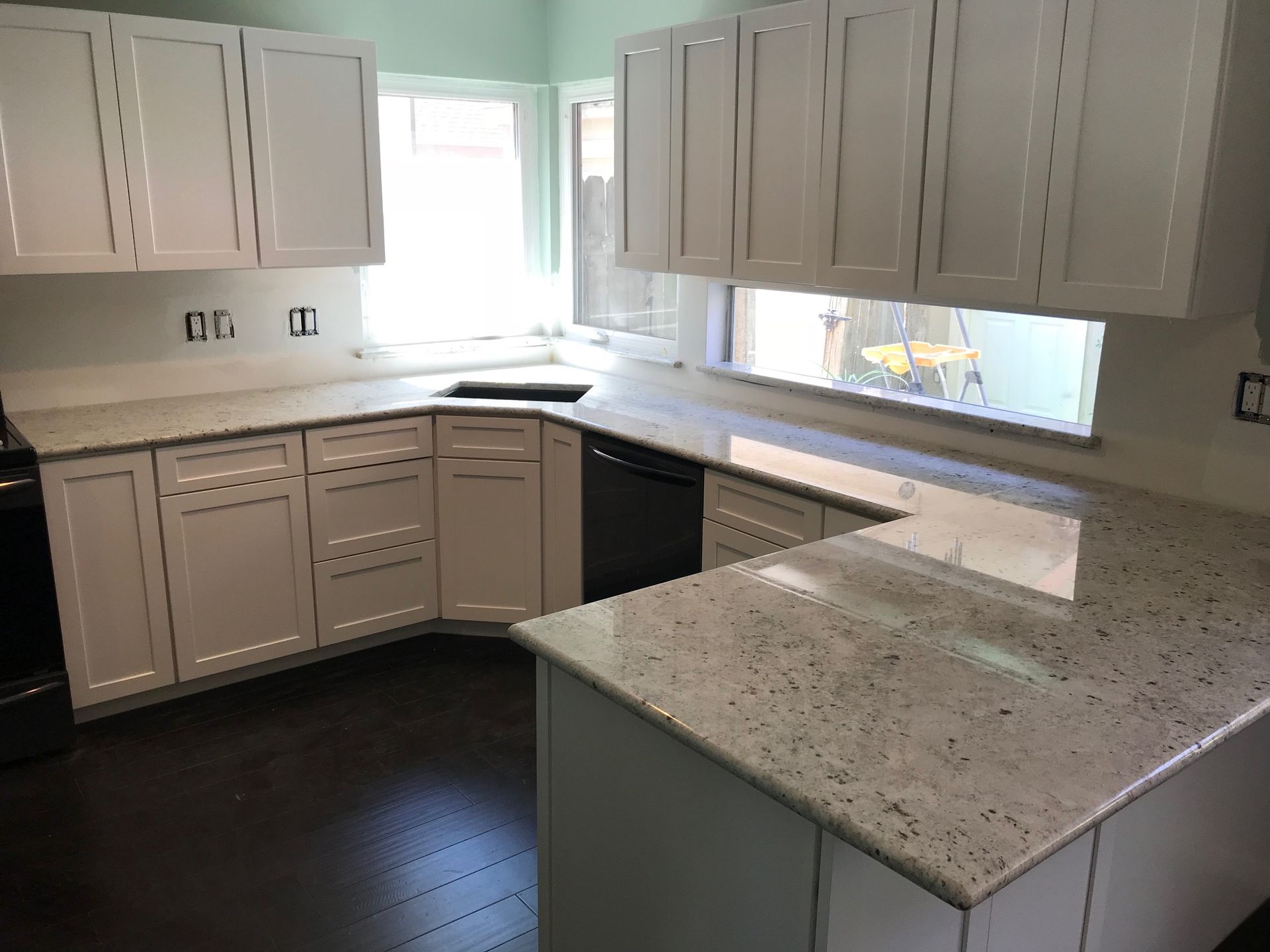 White kitchen cabinets with light speckled countertops.