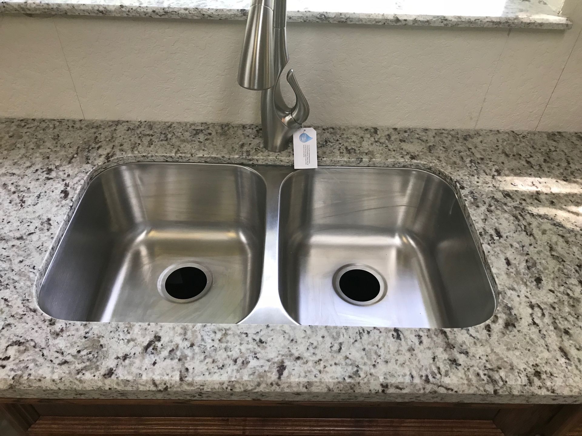 Stainless steel double sink in a kitchen with granite countertop.