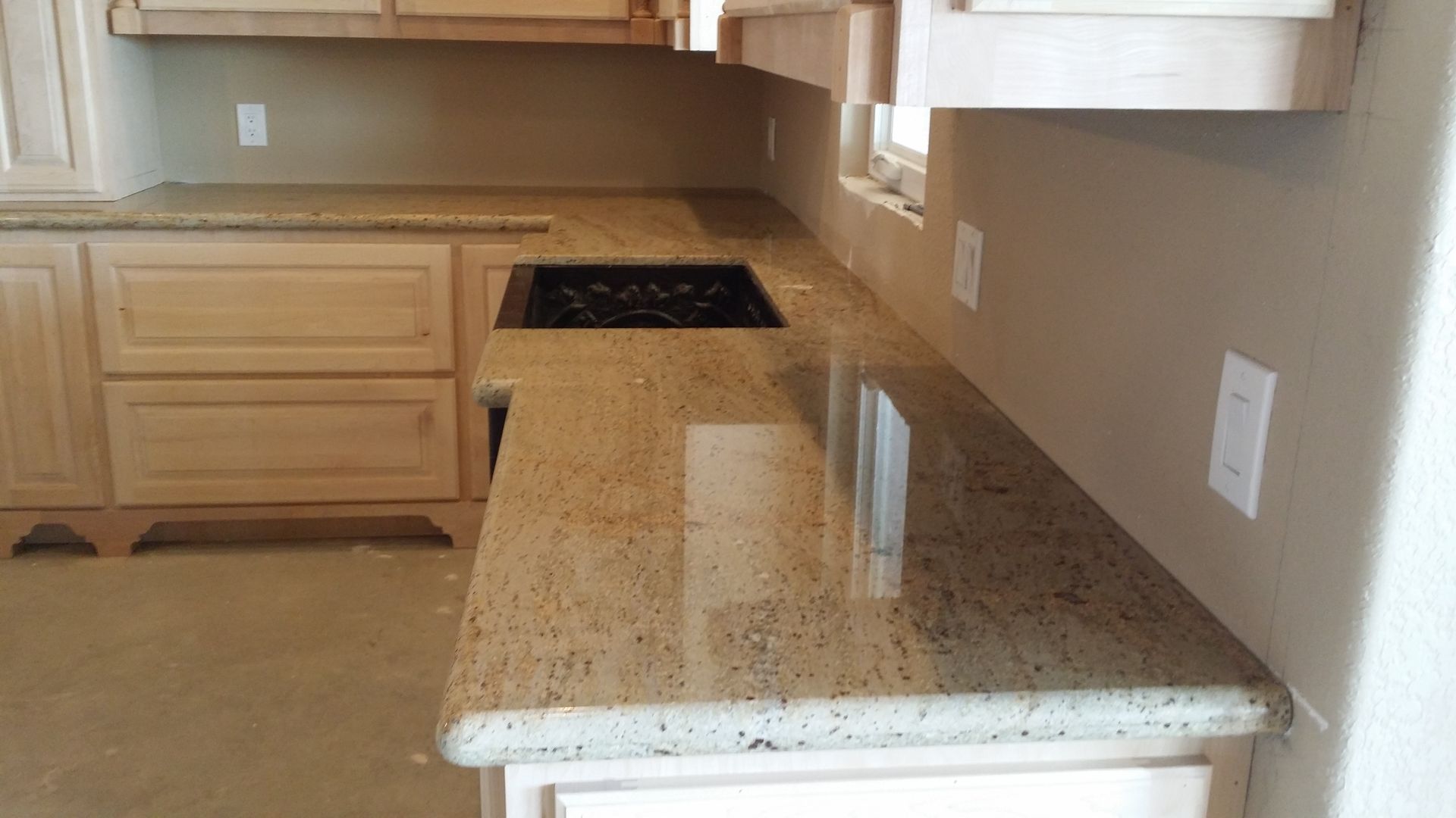 Kitchen with light-colored cabinets and granite countertops, electric cooktop, and beige walls.