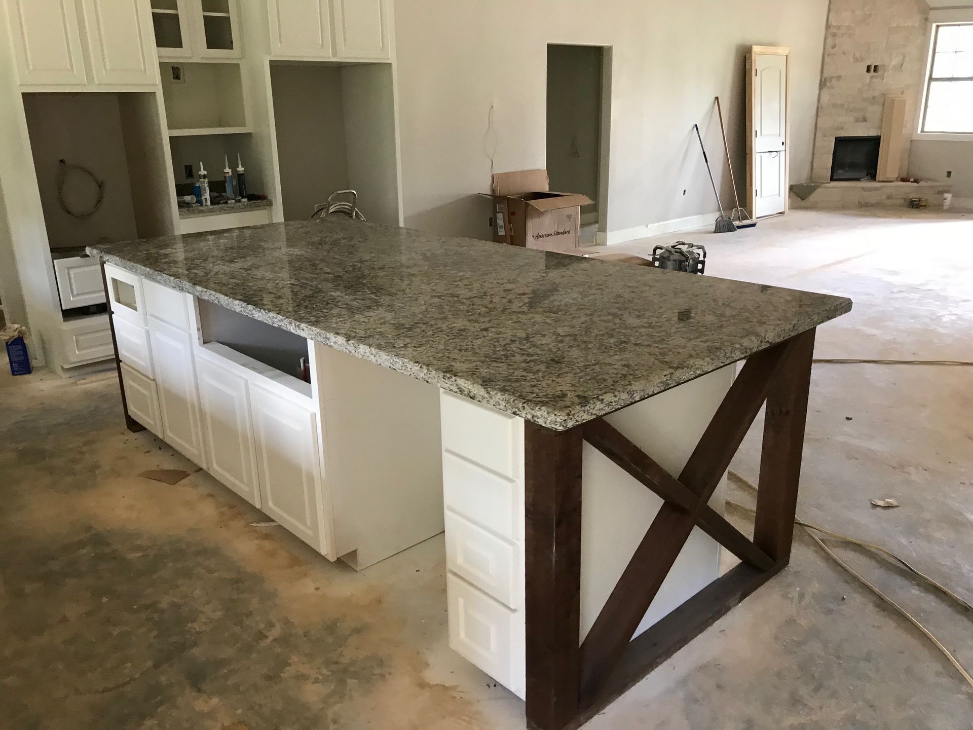 Kitchen island with granite countertop and white cabinets, unfinished. Brown