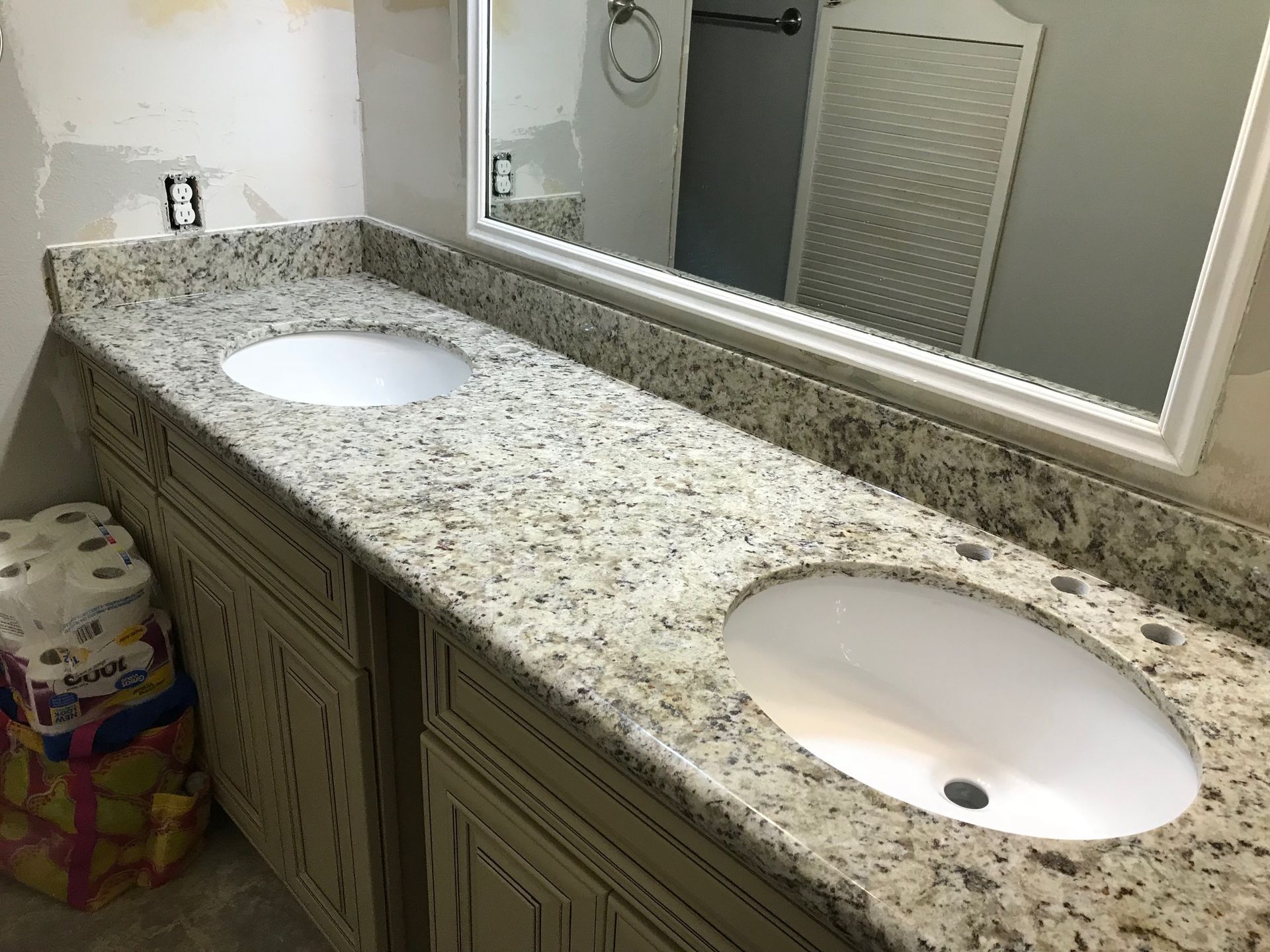 Bathroom vanity with two sinks, granite countertop, light cabinets, and large mirror.