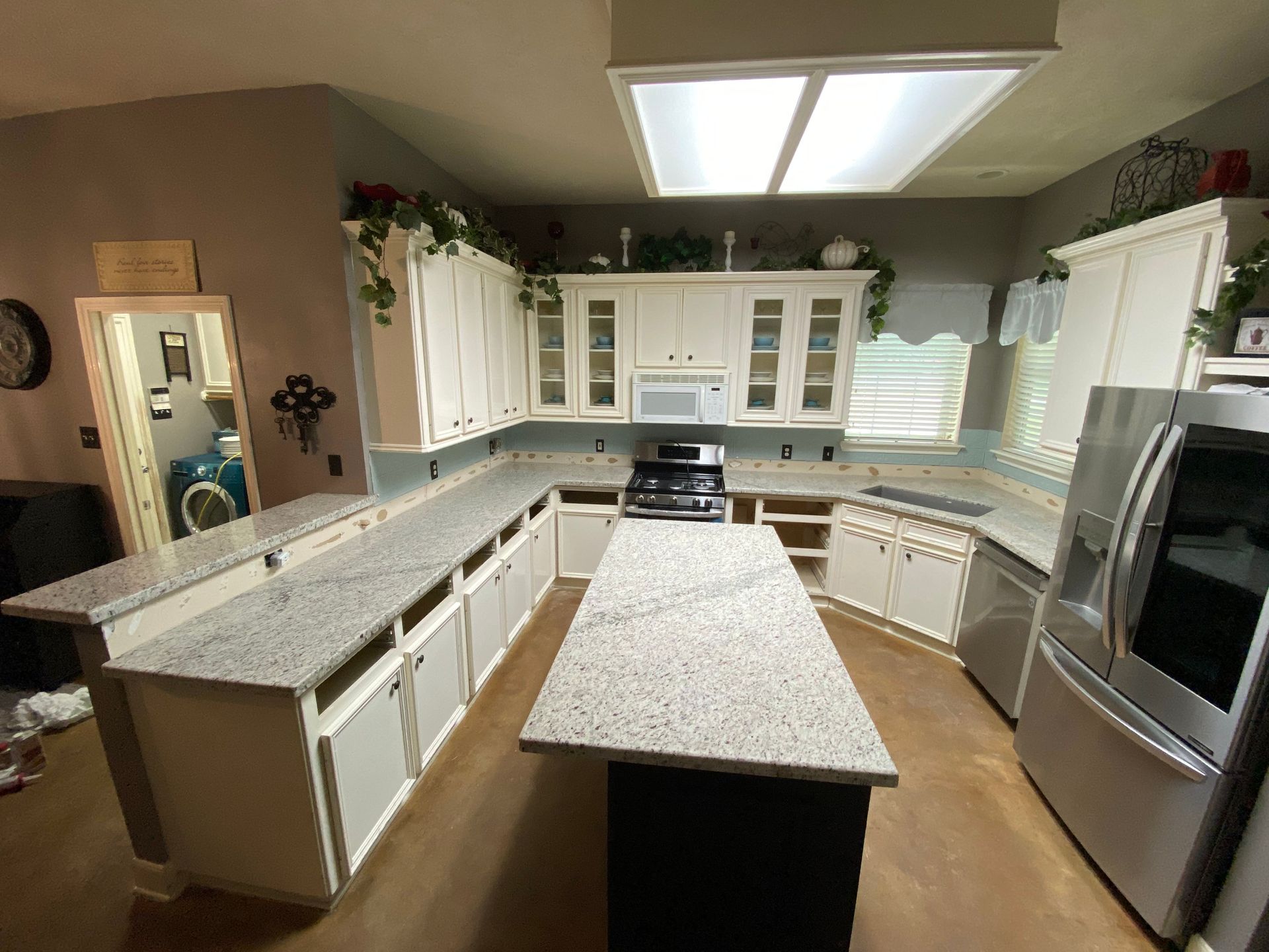 White kitchen with granite countertops, cabinets, and appliances. Island with dark base.