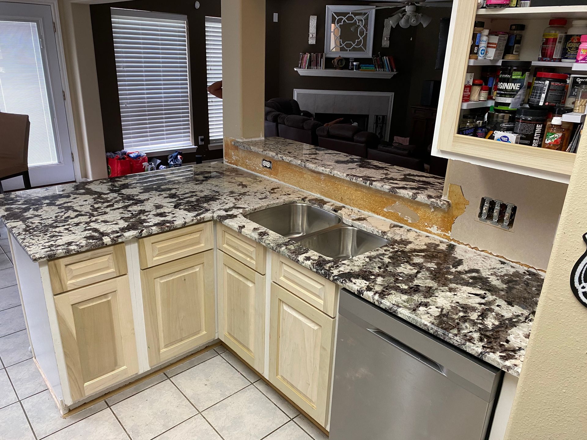 Kitchen with granite countertops, light wood cabinets, stainless steel appliances, and a double sink.