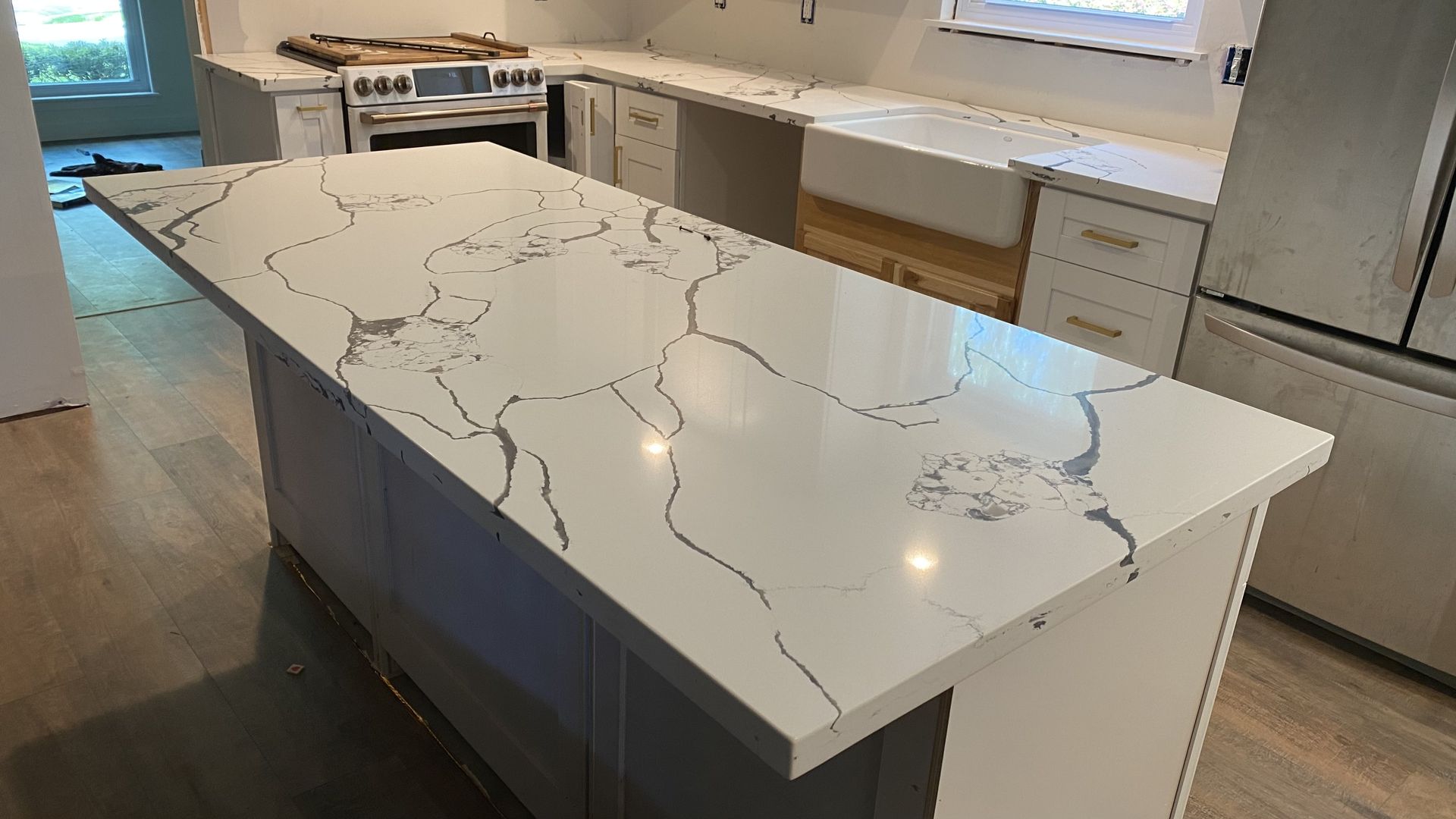 Modern kitchen with a large white marble-pattern island and stainless steel appliances