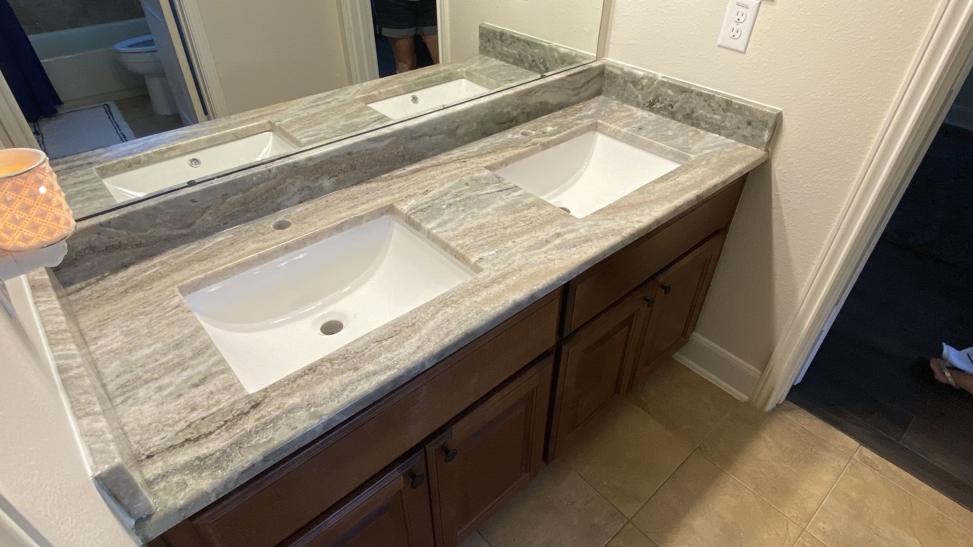 Bathroom with double vanity, light granite countertop, and two white sinks. Brown cabinets and a large mirror.