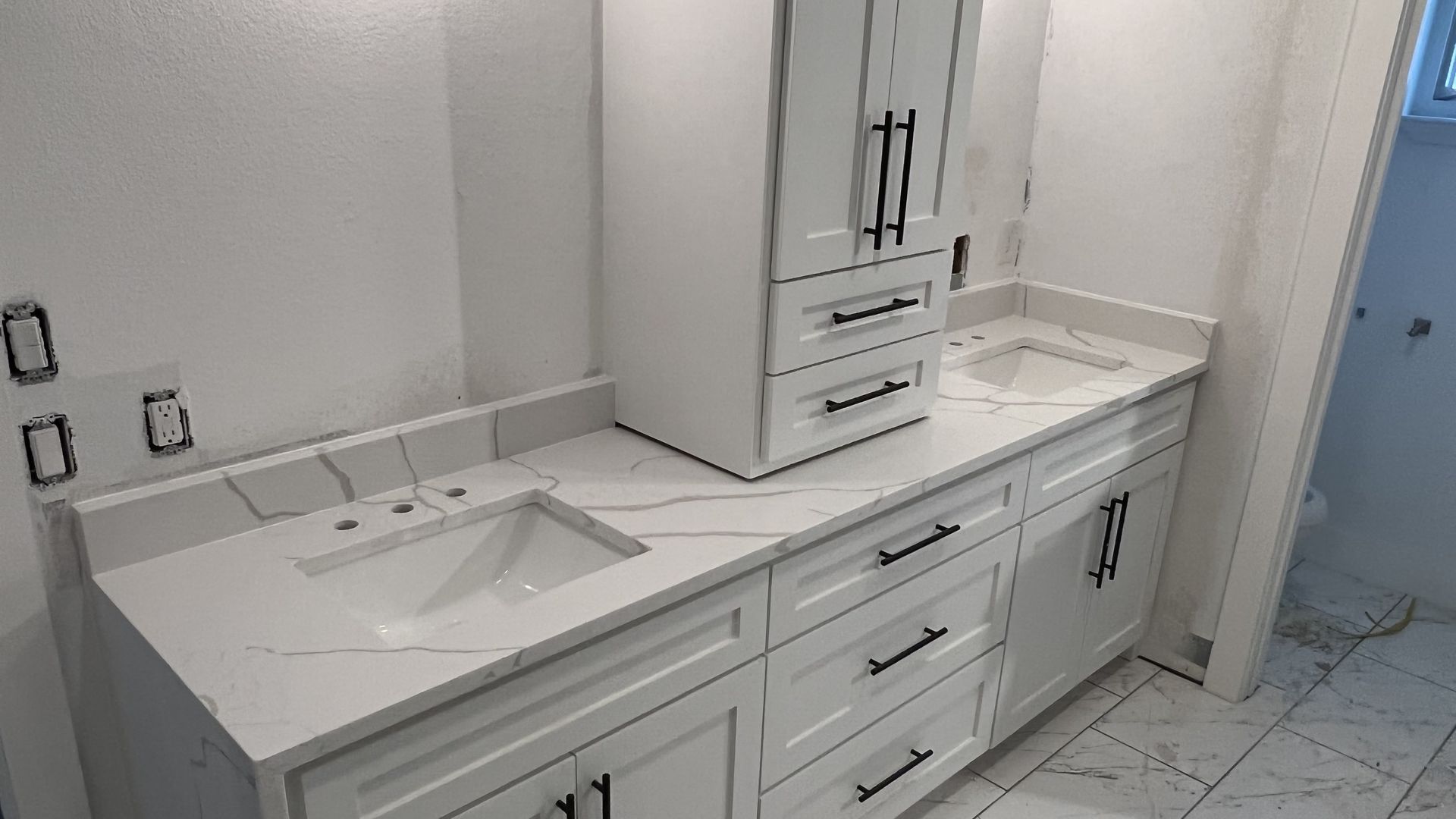 White bathroom vanity with marble countertop and storage cabinet.
