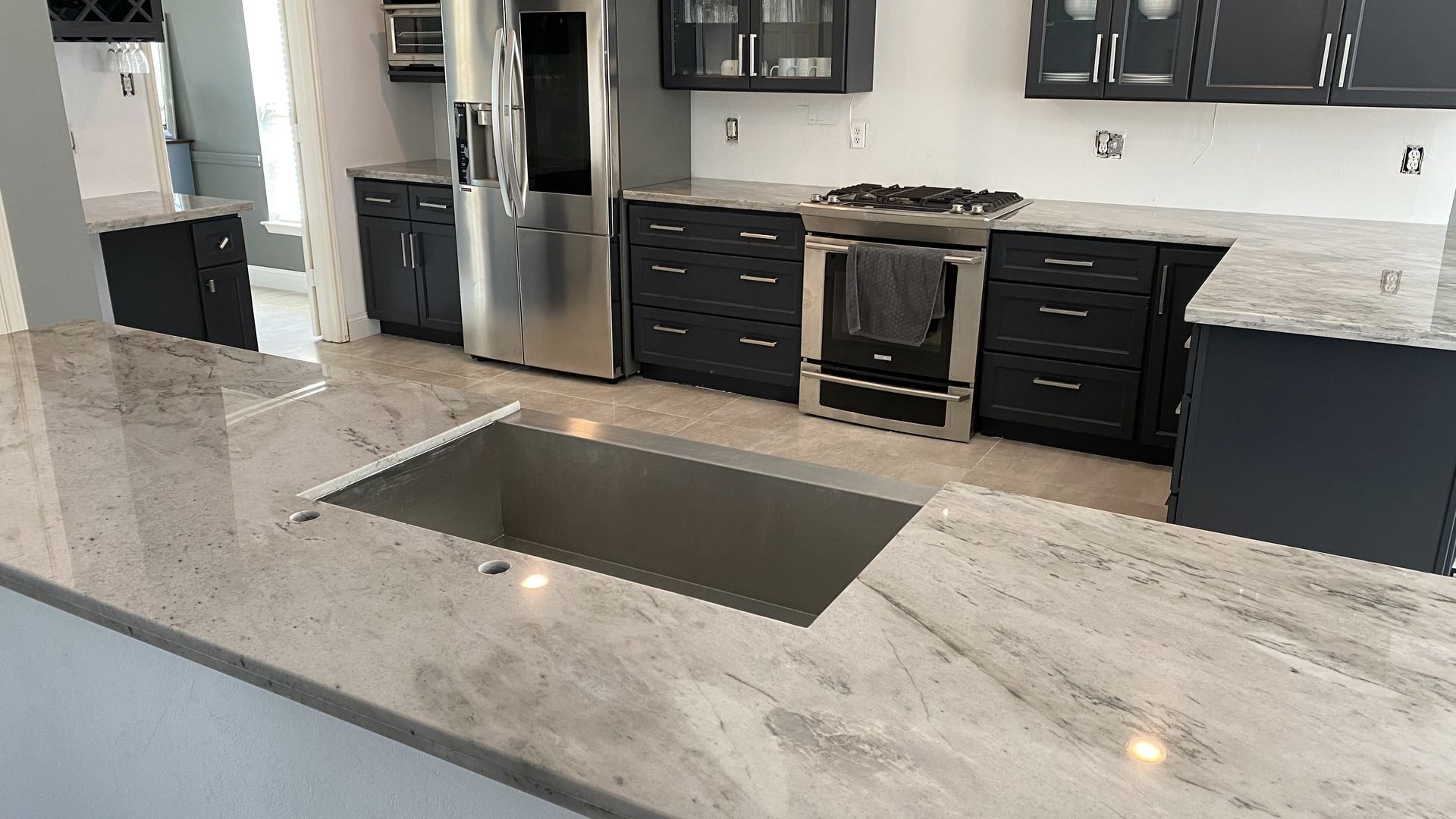 Modern kitchen with dark cabinets, stainless steel appliances, and light countertops.